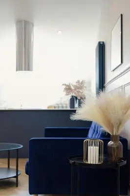 a blue couch with a vase of feathers on a table at Old Church Apartment 5 in Oban