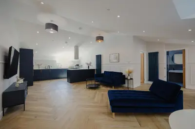 a living room with two blue couches and a kitchen at Old Church Apartment 5 in Oban