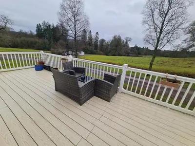 two chairs on a wooden deck with a fence at 10 lochview in Moffat