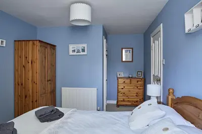 a blue bedroom with a bed and a dresser at Glenalbyn Cottage in Saint Fillans