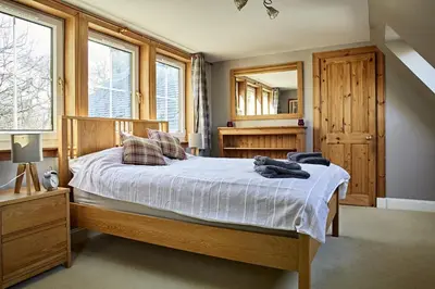 a bedroom with a bed and a large mirror at Glenalbyn Cottage in Saint Fillans