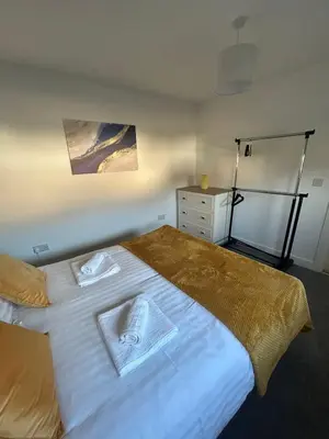 a bedroom with a large white bed with two towels at Plains Town House, Airdrie in Caldercruix