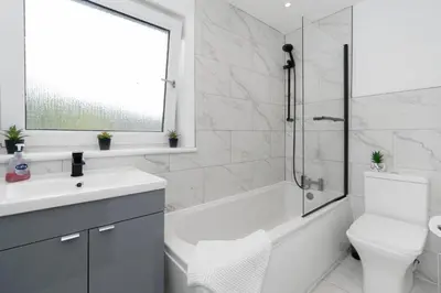 a white bathroom with a tub and a sink and a toilet at Stylish 4Bed Home Free Parking 20 Min to Edinburgh in Livingston