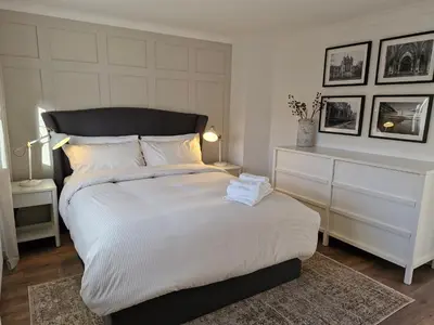 a bedroom with a large white bed with a black headboard at Justina's House in East Kilbride