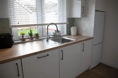 a kitchen with white cabinets and a sink and a window at Justina's House in East Kilbride