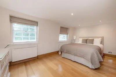 a white bedroom with a bed and two windows at Knightsbridge Duplex Two Bedroom Apartment in Moffat