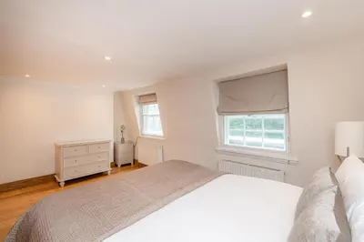 a white bedroom with a bed and a window at Knightsbridge Duplex Two Bedroom Apartment in Moffat