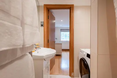a bathroom with a sink and a washing machine at Knightsbridge Duplex Two Bedroom Apartment in Moffat