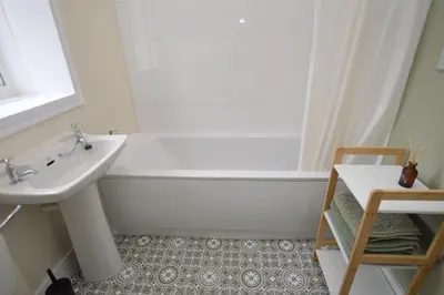 a bathroom with a white tub and a sink at Seascape in Kames