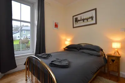 a bedroom with a bed with black sheets and a window at Secret Coast Getaway in Tighnabruaich