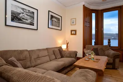 a living room with a couch and a table at Secret Coast Getaway in Tighnabruaich