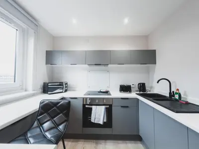 a white kitchen with a sink and a stove at Finnieston Apartment in Glasgow