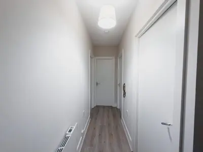 a hallway with a door and white walls and wood floors at Finnieston Apartment in Glasgow