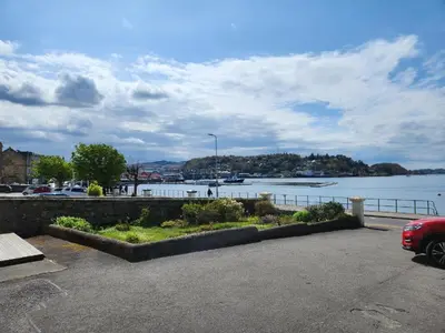 a car parked in a parking lot next to a body of water at No 1 Westbay Apartment in Dunollie