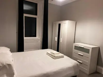 a bedroom with a bed and a dresser and a window at No 1 Westbay Apartment in Dunollie