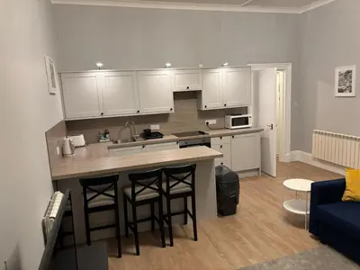 a kitchen with white cabinets and a blue couch at No 1 Westbay Apartment in Dunollie