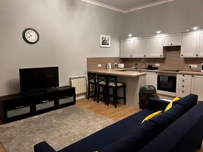 a living room with a couch and a kitchen at No 1 Westbay Apartment in Dunollie