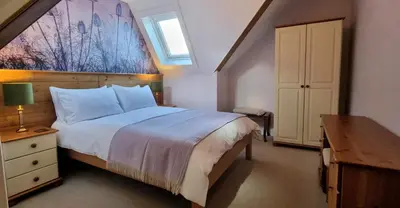 a bedroom with a bed and a desk and a window at Craigbuie Guesthouse in Killin