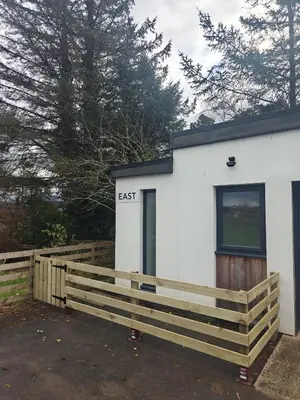 a white building with a fence in front of it at Viewpoint Pods in Dunollie