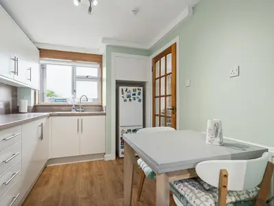 a kitchen with white cabinets and a table and chairs at Spacious 2 Bed in Falkirk in Falkirk