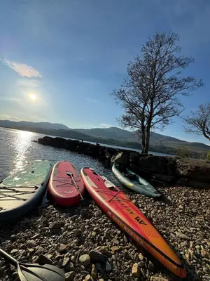 five kayaks are lined up on a rocky shore at Ardeonaig Lodge with Hot Tub & Water Fronted Games room in Ardeonaig