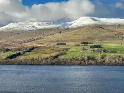 a snow covered mountain with a lake in front of it at Ardeonaig Lodge with Hot Tub & Water Fronted Games room in Ardeonaig