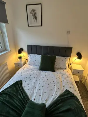 a bedroom with a large bed with green pillows at 3BR Home Sleeps 10 with Private Drive Near Park in Newton Mearns
