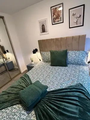 a bedroom with a large bed with green pillows at 3BR Home Sleeps 10 with Private Drive Near Park in Newton Mearns