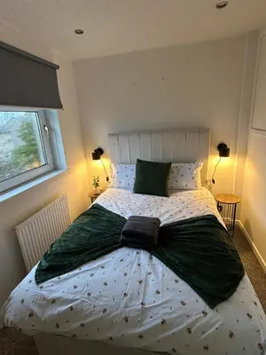 a bedroom with a large bed with green sheets at 3BR Home Sleeps 10 with Private Drive Near Park in Newton Mearns