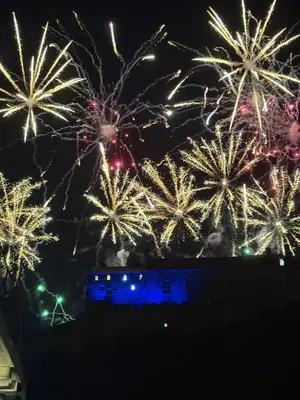 a bunch of fireworks exploding in the sky over a building at Castle flat in Edinburgh in Edinburgh