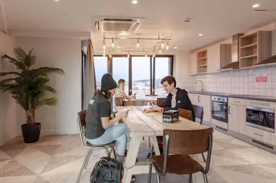 two people sitting at a table in a kitchen at For Students Only Stylish Studios in Glasgow in Glasgow