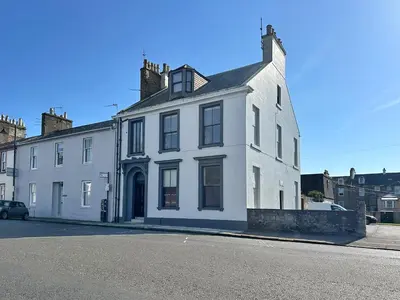 a white house sitting on the side of a street at The Penthouse - Beachwalk Apartments in Ayr