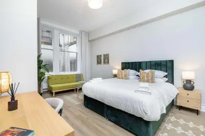 a bedroom with a large bed and a table and chair at The Sauchie in Glasgow