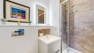a white bathroom with a sink and a shower at The Sauchie in Glasgow