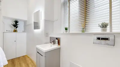 a white bathroom with a sink and a window at The Sauchie in Glasgow