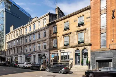 a building on a city street with parked cars at The Sauchie in Glasgow