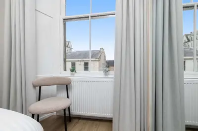 a bedroom with a chair in front of a window at The Sauchie in Glasgow
