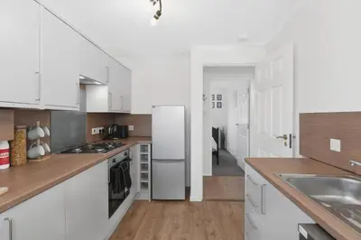 a kitchen with white cabinets and a refrigerator at Cozy Edinburgh 2BR with CAR parking in Edinburgh