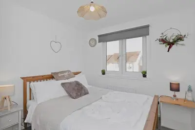 a white bedroom with a bed and a window at Cozy Edinburgh 2BR with CAR parking in Edinburgh