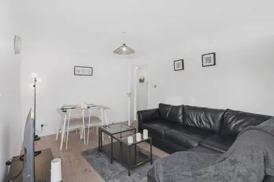 a living room with a black leather couch and a table at Cozy Edinburgh 2BR with CAR parking in Edinburgh