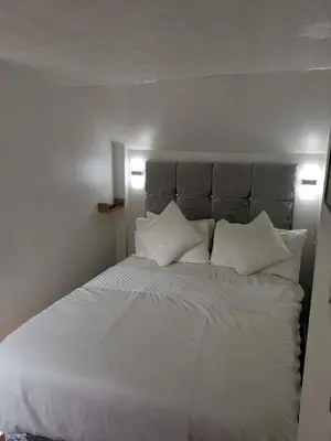 a bed with white sheets and pillows in a bedroom at Glenfern Guest House and a separate Cottage with its own private hot tub in Balloch