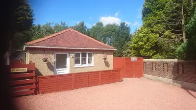 a small house with a red fence in front of it at Glenfern Guest House and a separate Cottage with its own private hot tub in Balloch