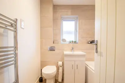 a bathroom with a toilet and a sink and a window at Angel House - 3 bedrooms close to Airdrie Centre in Airdrie