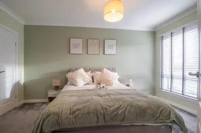 a bedroom with a large bed and a window at Catriona House - 3 Bedroom house in Motherwell in Holytown