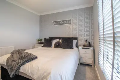 a bedroom with a bed and a sign on the wall at Catriona House - 3 Bedroom house in Motherwell in Holytown