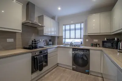 a kitchen with white cabinets and a washer and dryer at Catriona House - 3 Bedroom house in Motherwell in Holytown