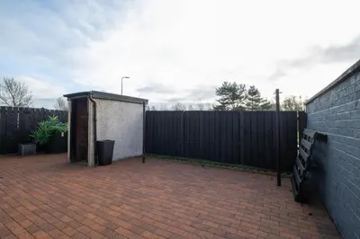 a backyard with a fence and a shed at Catriona House - 3 Bedroom house in Motherwell in Holytown