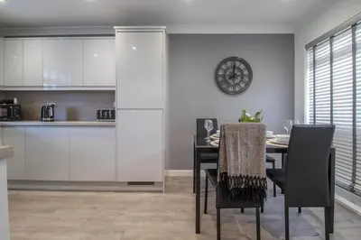 a kitchen and dining room with a table and a clock at Catriona House - 3 Bedroom house in Motherwell in Holytown