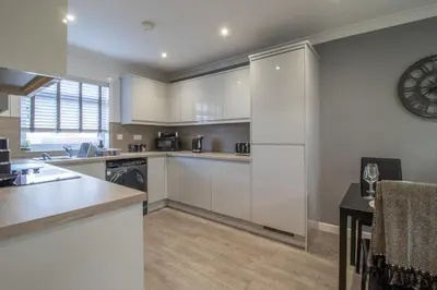 a large kitchen with white cabinets and a table at Catriona House - 3 Bedroom house in Motherwell in Holytown