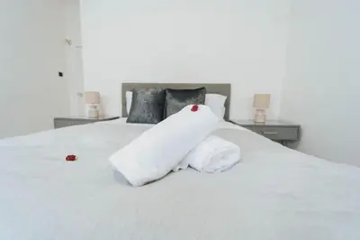a white towel on a bed with two roses on it at Top Floor 1BR Wishaw Flat with Parking in Wishaw
